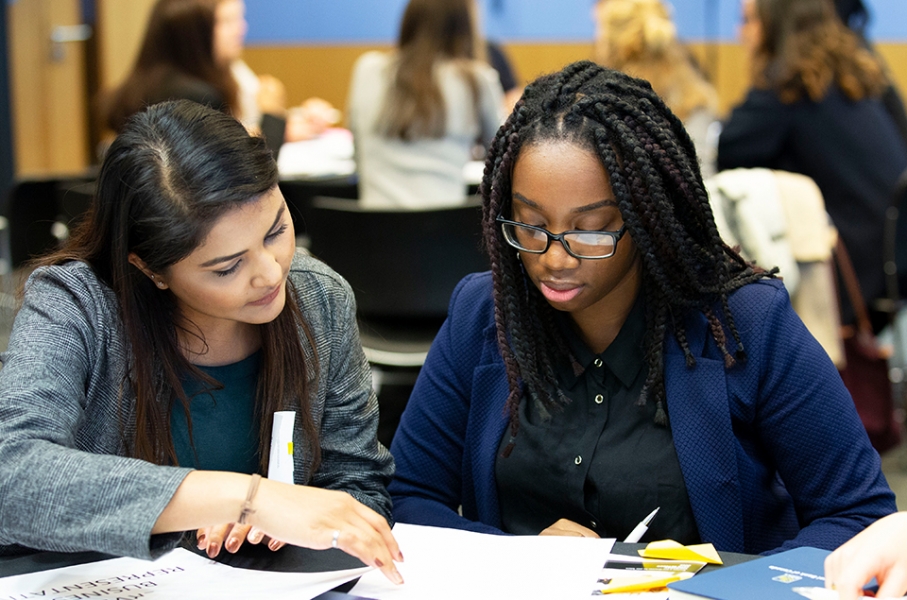 Two female-identifying students sitting and working together during a Cityview event