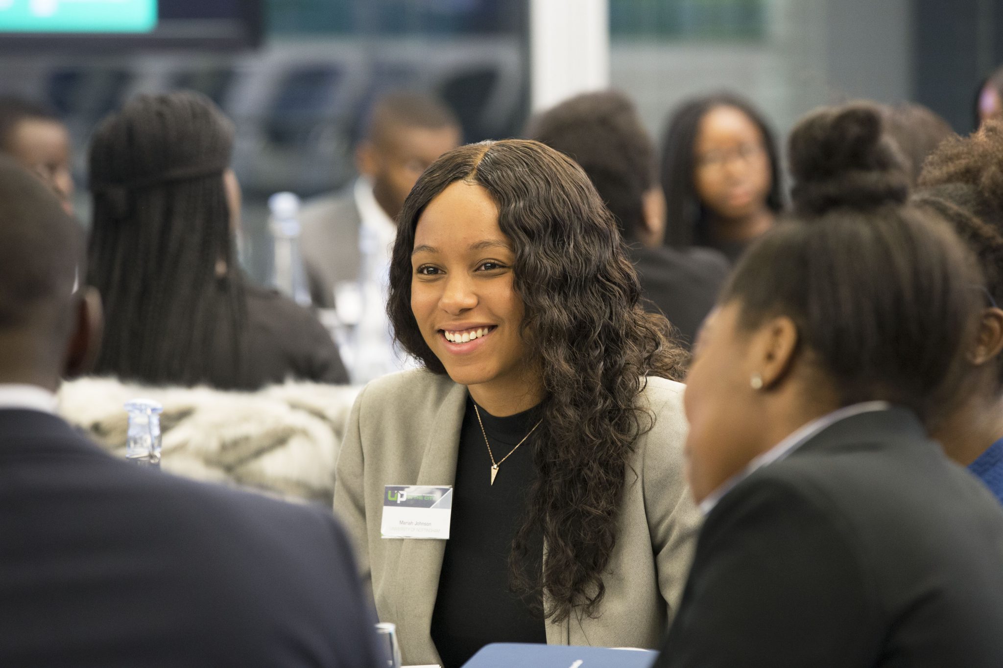 Diverse student sitting and smiling during an Uncovering Prospects event